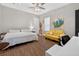 Cozy bedroom featuring wood floors, a patterned bedspread, and a bright yellow love seat at 11015 Hawkshead Ct, Windermere, FL 34786