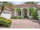 Charming home featuring a brick paved driveway, arched entryway, and mature landscaping at 11015 Hawkshead Ct, Windermere, FL 34786