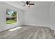 This bedroom features bright natural light, a ceiling fan, and sleek, modern gray wood flooring at 1406 Sean Ct, St Cloud, FL 34772