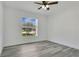 This bedroom features bright natural light, a ceiling fan, and sleek, modern gray wood flooring at 1406 Sean Ct, St Cloud, FL 34772