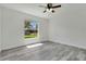 This bedroom features bright natural light, a ceiling fan, and sleek, modern gray wood flooring at 1406 Sean Ct, St Cloud, FL 34772