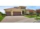 Elegant home featuring a three-car garage, meticulously landscaped yard, and a paver driveway for enhanced curb appeal at 15344 Johns Lake Pointe Blvd, Winter Garden, FL 34787