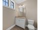 A cozy powder room with tiled floors, a toilet, a vanity sink, decorative lighting, and a window at 15344 Johns Lake Pointe Blvd, Winter Garden, FL 34787