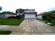 Two-story home with a two-car garage, concrete driveway, and manicured front lawn with tropical landscaping at 208 Oleander St, Winter Haven, FL 33881