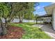 Scenic backyard featuring a large shade tree, manicured lawn, covered patio, and a white privacy fence at 2112 Fosgate Dr, Winter Park, FL 32789