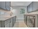 Modern laundry room features gray cabinets, subway tile backsplash, and front load washer and dryer at 2112 Fosgate Dr, Winter Park, FL 32789