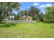 Charming yellow home is surrounded by trees and features a white picket fence and well-manicured lawn at 244 N Leavitt Ave, Orange City, FL 32763