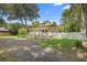 Charming cottage with a gravel driveway and white picket fence, surrounded by lush landscaping at 244 N Leavitt Ave, Orange City, FL 32763