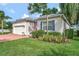 Charming home exterior features lush landscaping, an American flag, and a brick-paved driveway at 2500 Castle Pines St, Clermont, FL 34711