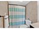 Well-maintained bathroom with a turquoise-striped shower curtain and neutral tiled walls at 2947 S Atlantic Ave # 601, Daytona Beach, FL 32118