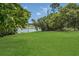 Large, grassy backyard featuring mature trees, lush greenery, and lake views at 2990 E Central Ave, Bartow, FL 33830