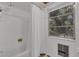 Bright bathroom featuring a shower with white tile and shower curtain, and a window with a view of trees outside at 2990 E Central Ave, Bartow, FL 33830