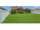 Spacious backyard with green grass, white fence, and tropical foliage at 3009 Park Ridge Ave, Mulberry, FL 33860