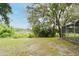 Expansive backyard featuring lush grass, mature trees with Spanish moss, and a screened-in pool enclosure, perfect for outdoor living at 33042 Lake Bend Cir, Leesburg, FL 34788