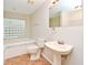 Full bathroom with pedestal sink, tub with tile surround, and unique glass block window at 33042 Lake Bend Cir, Leesburg, FL 34788