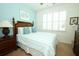 Bedroom featuring a blue accent wall, plantation shutters, and wooden bed frame at 3574 La Jolla Dr, Clermont, FL 34711