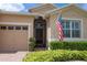 Charming home showcasing a covered entry, manicured shrubs, and an American flag display at 3574 La Jolla Dr, Clermont, FL 34711