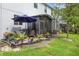 Landscaped backyard with a screened-in porch, patio furniture, umbrella, and various plants at 366 Reed Grass Dr, Oviedo, FL 32765