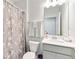 Clean bathroom with white vanity, toilet, mirror, and a floral patterned shower curtain for a fresh look at 378 Cape Honeysuckle Pl, Sanford, FL 32771