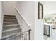 Carpeted staircase with white railing, adjacent to a kitchen area, providing access to the upper level at 378 Cape Honeysuckle Pl, Sanford, FL 32771