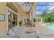 A screened patio features a comfortable seating area with a stone floor and view of the backyard pool at 4048 Gilder Rose Pl, Winter Park, FL 32792