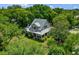 Aerial view of a light-colored, two-story home surrounded by mature trees and lush landscaping at 408 W Pearl St, Minneola, FL 34715