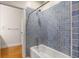 Bathroom with blue tiled shower, tub, and wooden floors outside the door at 408 W Pearl St, Minneola, FL 34715