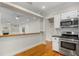 Open kitchen view showcases white cabinets, stainless appliances, and breakfast bar to the living room at 408 W Pearl St, Minneola, FL 34715
