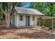 Cute shed with blue door and metal roof sitting in the backyard with grass and shade trees at 408 W Pearl St, Minneola, FL 34715