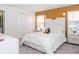 Cozy bedroom with white bed, closet, nightstand and a gold colored accent wall at 4912 Windermere Ave, Kissimmee, FL 34746