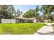 Home on a lush lawn features a privacy fence, solar panels, a two-car garage, and is enveloped by mature trees at 5177 Chesapeake Ave, Orlando, FL 32808