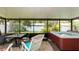 Enclosed sunroom featuring a hot tub, tiled floors, screened windows, patio seating, and peaceful backyard views at 5177 Chesapeake Ave, Orlando, FL 32808