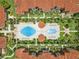 Aerial view of community pools, lush landscaping, red tile roofs, and inviting layout, creating a serene environment at 5512 Metrowest Blvd # 201, Orlando, FL 32811