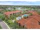 Aerial view of resort-style community featuring red tile roofs, lush landscaping, a pool, and a lake view at 5512 Metrowest Blvd # 201, Orlando, FL 32811