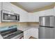 Modern kitchen features stainless steel appliances, white cabinets, and granite countertops at 5512 Metrowest Blvd # 201, Orlando, FL 32811