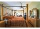 Comfortable bedroom featuring a four-poster bed, ceiling fan, hardwood floors, and a cozy sitting area with a fireplace at 742 Seneca Trl, St Cloud, FL 34772