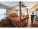 Comfortable bedroom featuring a four-poster bed, ceiling fan, hardwood floors, and a cozy sitting area with a fireplace at 742 Seneca Trl, St Cloud, FL 34772