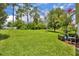 Lush backyard with mature trees, beautiful landscaping, and an open grassy area at 7834 Minutemen Loop, Winter Garden, FL 34787
