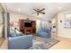 Cozy living room with comfortable blue couches, ceiling fan, TV with entertainment center, and access to Florida room at 8865 Se 119Th St, Summerfield, FL 34491