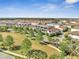 An aerial view showcases townhomes with a common green space, mature trees, and sidewalks in a well-maintained neighborhood at 9533 Mere Pkwy, Orlando, FL 32832