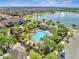 An aerial shot exhibits the pool and amenity center nestled amongst palm trees with a serene lake backdrop in the community at 9533 Mere Pkwy, Orlando, FL 32832