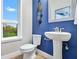 Stylish powder room with blue accent wall, pedestal sink and decorative mirror creating a chic and inviting space at 9533 Mere Pkwy, Orlando, FL 32832
