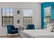 Bedroom with blue accent wall, two windows, seating area, and serene decor at 1041 Castle Pines Ct, Reunion, FL 34747