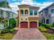Charming two-story home with a tile roof, red garage doors, and beautifully landscaped front yard at 1041 Castle Pines Ct, Reunion, FL 34747