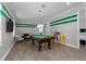 Open game room with pool table, stylish furniture, and green-striped accent wall at 1041 Castle Pines Ct, Reunion, FL 34747