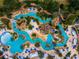 Aerial view capturing a sprawling water park, meandering waterways, sun loungers, and vibrant umbrellas at 1041 Castle Pines Ct, Reunion, FL 34747
