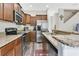 Well-equipped kitchen featuring stainless steel appliances, granite countertops, wooden cabinetry, and modern flooring at 10656 Savannah Plantation Ct, Orlando, FL 32832