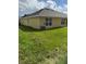 Exterior view of home's backyard showcasing manicured lawn and central air conditioning unit at 107 Athabasca Dr, Poinciana, FL 34759