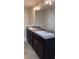 Bathroom featuring double sinks, granite countertops and dark wood cabinetry at 107 Athabasca Dr, Poinciana, FL 34759