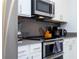 Close up of a modern kitchen featuring stainless steel appliances and gray backsplash at 1070 Splash Shot Pl, Davenport, FL 33896